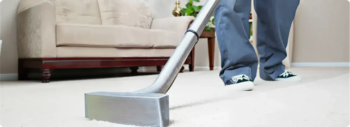 Carpet cleaning technician using a hot-water extraction wand on a light-colored carpet in a living room, Hialeah, FL.