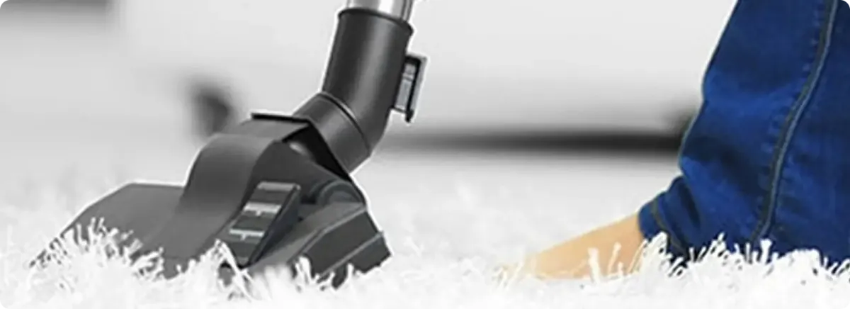 Close-up of a professional vacuuming a white carpet in Miami Gardens.